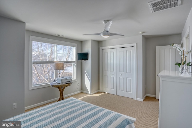 bedroom featuring ceiling fan, a closet, and light carpet