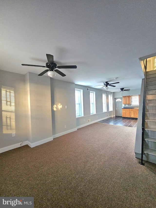 empty room featuring ceiling fan and dark colored carpet