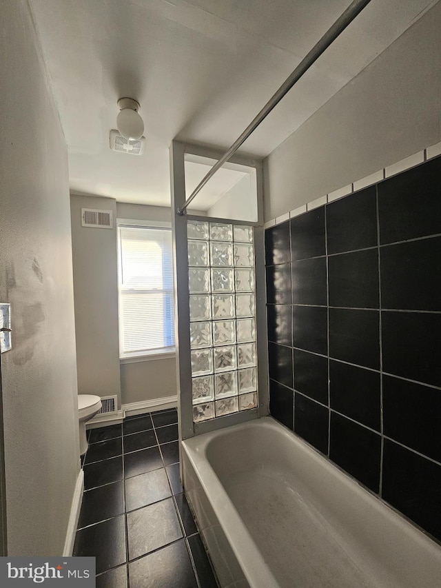 bathroom with tile patterned floors, a washtub, and toilet