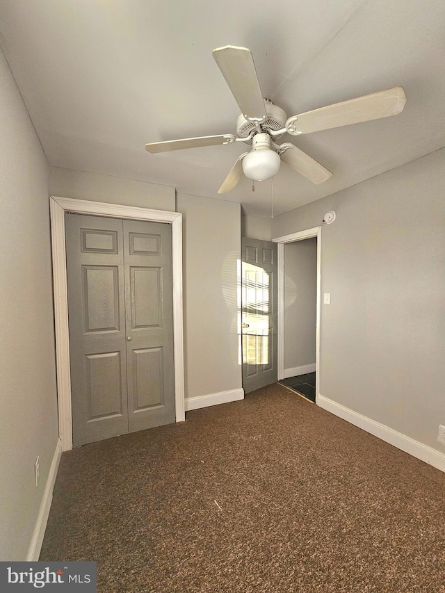 unfurnished bedroom featuring dark colored carpet, ceiling fan, and a closet