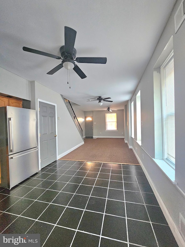 unfurnished living room with dark colored carpet and ceiling fan