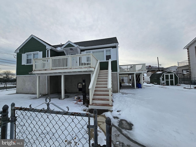 view of front of house featuring an outbuilding, fence, a shed, a wooden deck, and stairs