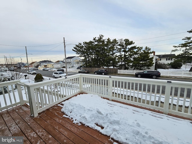 snow covered deck with a residential view and fence