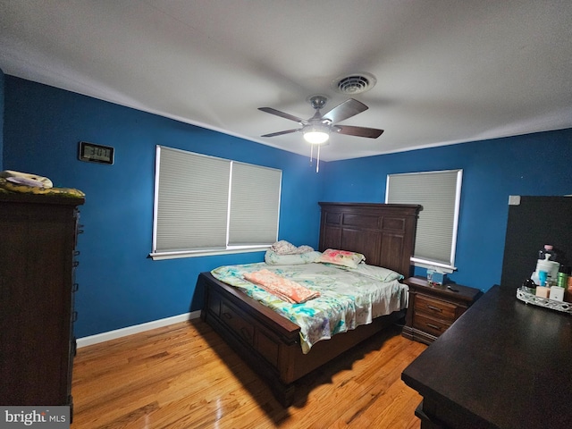 bedroom with ceiling fan, light wood finished floors, visible vents, and baseboards