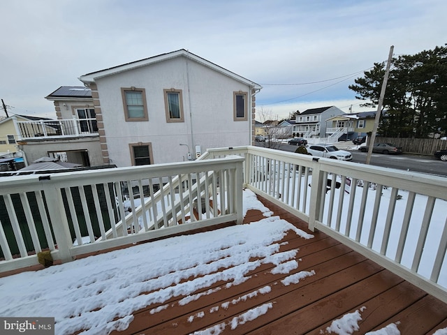 snow covered deck featuring a residential view