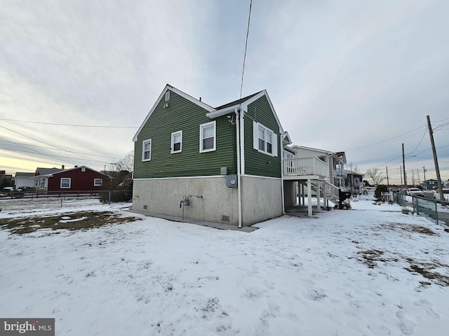 snow covered property featuring fence and a wooden deck