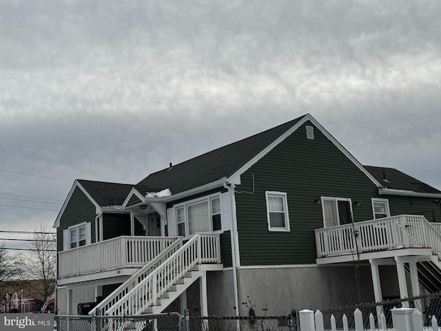 exterior space featuring a porch, stairway, and a fenced front yard