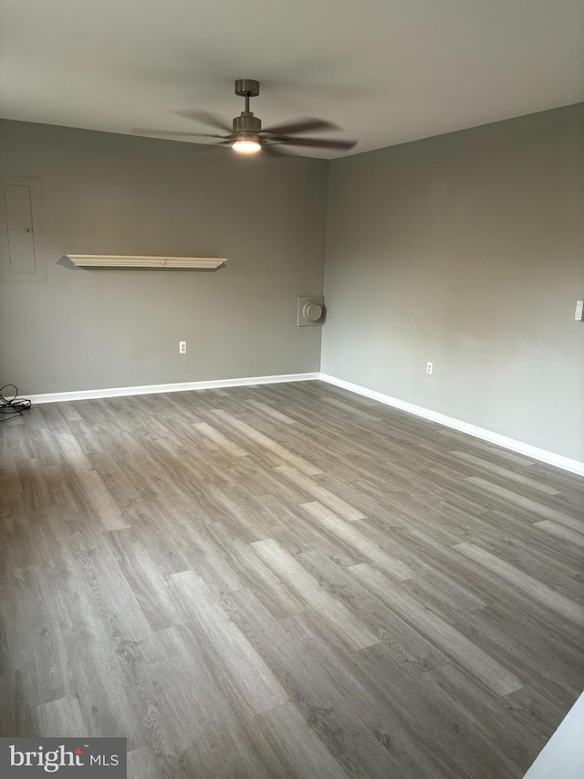 empty room with light wood-type flooring, ceiling fan, and electric panel