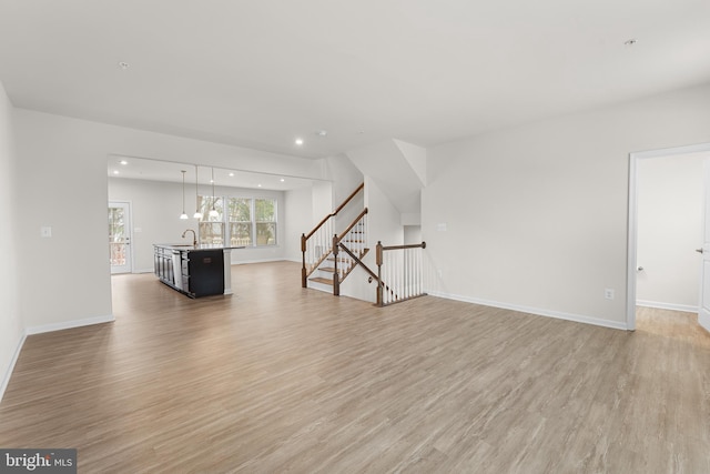 unfurnished living room featuring light hardwood / wood-style floors and sink