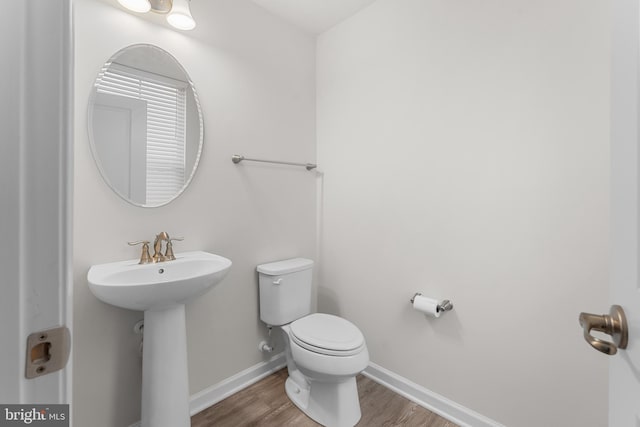 bathroom with toilet, hardwood / wood-style floors, and sink