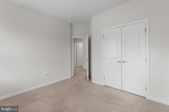 unfurnished bedroom featuring light carpet and a closet