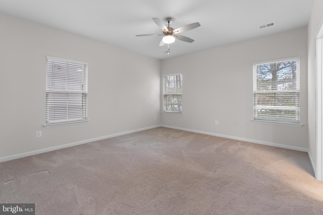 carpeted empty room featuring ceiling fan and a wealth of natural light