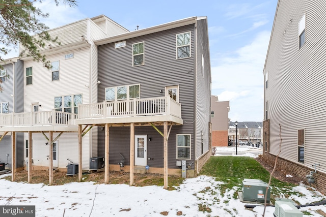 snow covered rear of property with a wooden deck and central air condition unit