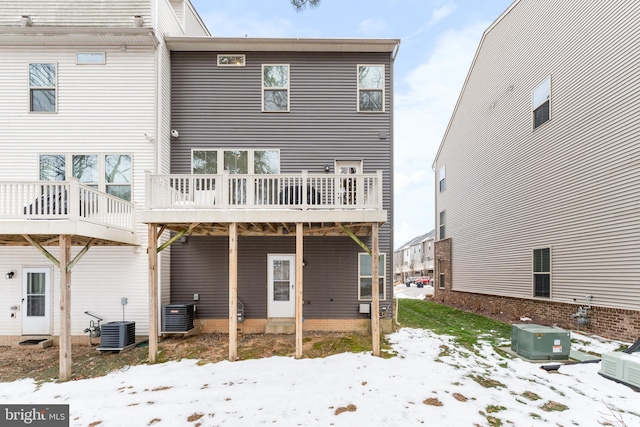 snow covered back of property featuring central AC unit and a deck