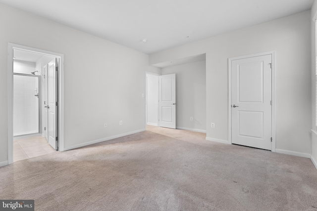 unfurnished bedroom featuring light colored carpet and connected bathroom