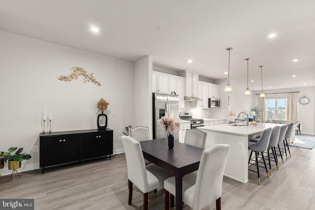 dining space with sink and light hardwood / wood-style flooring