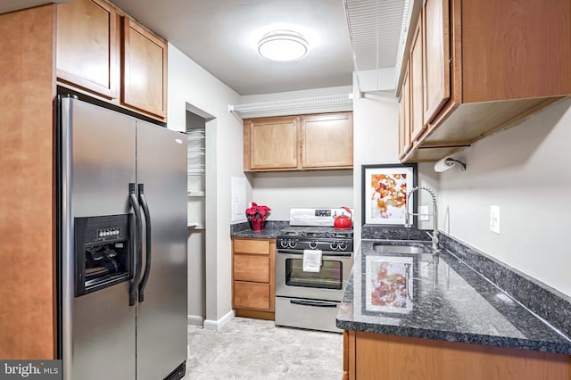 kitchen with appliances with stainless steel finishes, dark stone counters, and sink