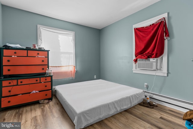 bedroom featuring hardwood / wood-style floors, cooling unit, and a baseboard heating unit