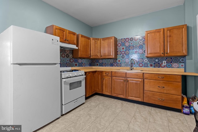 kitchen with decorative backsplash, white appliances, and sink