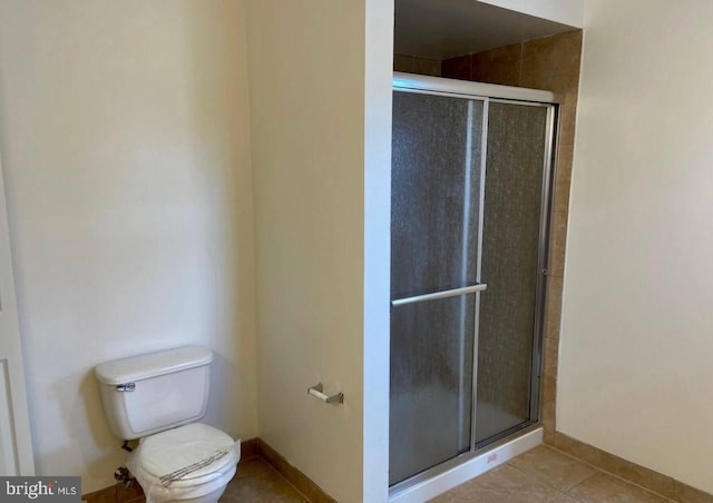 bathroom featuring tile patterned flooring, toilet, and a shower with shower door