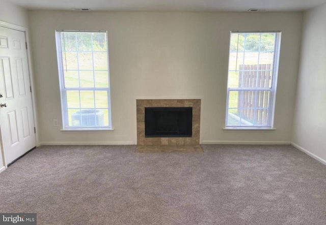 unfurnished living room featuring light carpet and a tiled fireplace