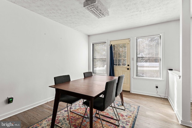 dining room featuring a chandelier, a textured ceiling, and light hardwood / wood-style floors