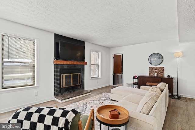 living room with a large fireplace, light wood-type flooring, and a textured ceiling