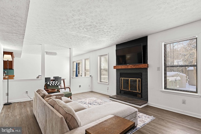 living room with a textured ceiling, wood-type flooring, and a fireplace