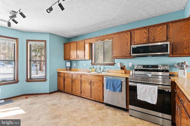 kitchen featuring sink, rail lighting, a textured ceiling, and appliances with stainless steel finishes