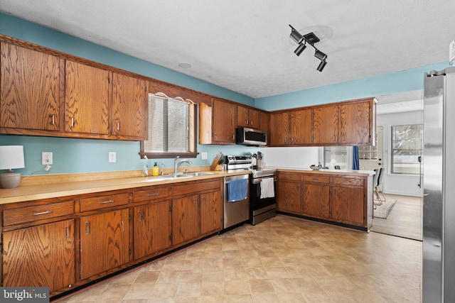 kitchen featuring appliances with stainless steel finishes, a textured ceiling, track lighting, and sink