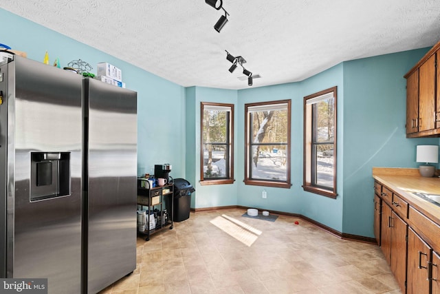 kitchen with stainless steel fridge with ice dispenser, rail lighting, and a textured ceiling