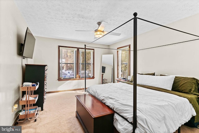 bedroom featuring ceiling fan, light colored carpet, and a textured ceiling