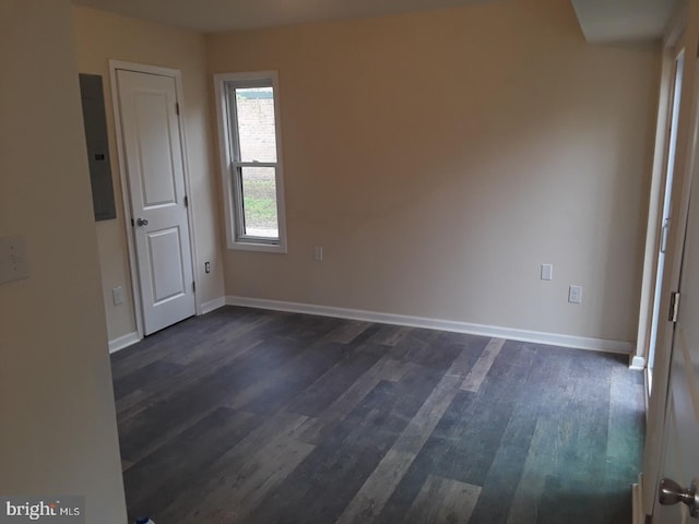 empty room with dark hardwood / wood-style floors and electric panel