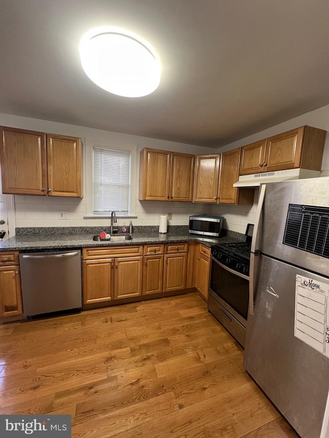 kitchen with decorative backsplash, sink, stainless steel appliances, and light hardwood / wood-style floors