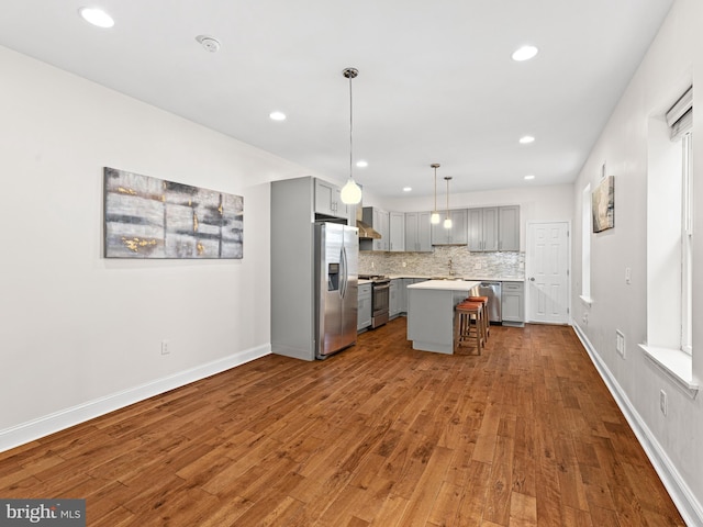 kitchen with backsplash, stainless steel appliances, pendant lighting, gray cabinets, and a kitchen island