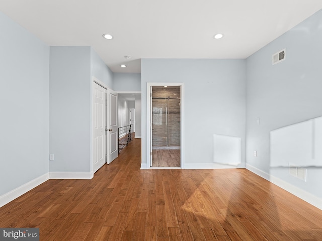 unfurnished bedroom with wood-type flooring and connected bathroom