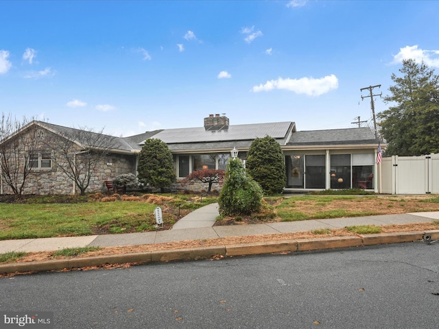 single story home with a front lawn and solar panels