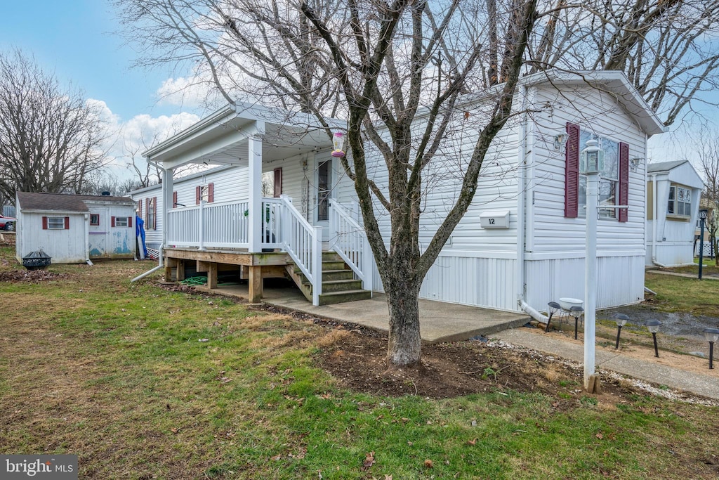 view of side of property with a lawn, an outbuilding, and covered porch