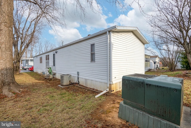 view of property exterior with central AC and a lawn