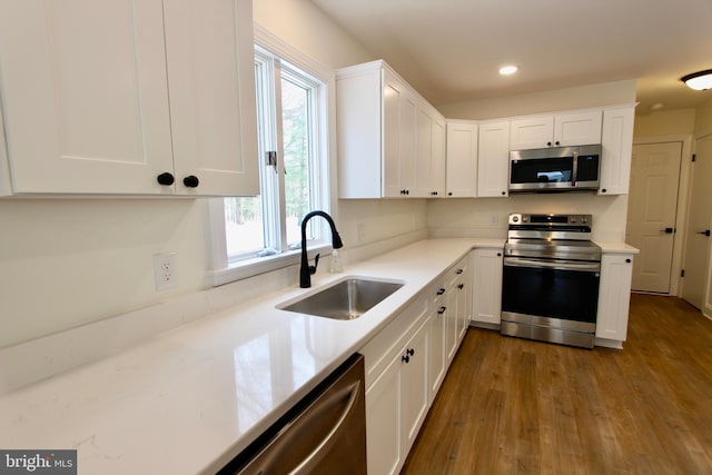 kitchen with sink, white cabinets, hardwood / wood-style floors, and appliances with stainless steel finishes