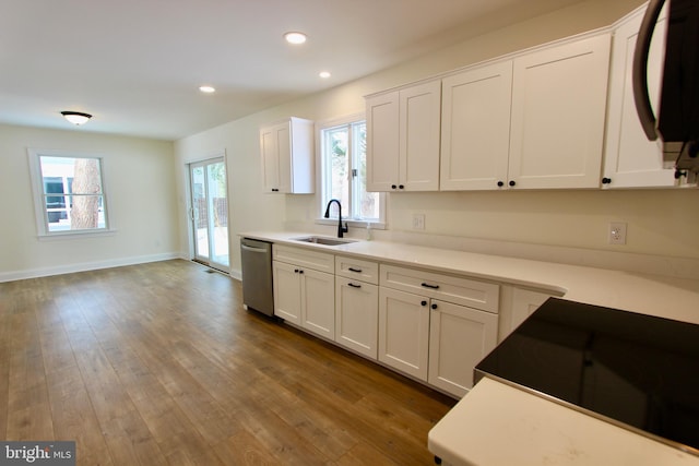 kitchen featuring dishwasher, sink, white cabinets, and wood-type flooring