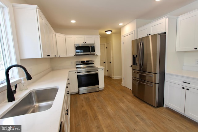 kitchen featuring white cabinetry, sink, appliances with stainless steel finishes, and light hardwood / wood-style flooring