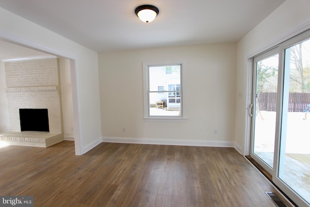 unfurnished living room featuring dark hardwood / wood-style floors and a brick fireplace