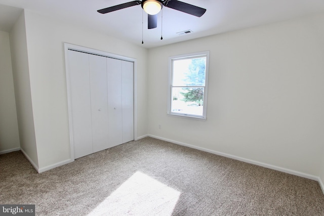 unfurnished bedroom with carpet, a closet, and ceiling fan