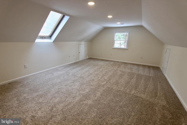 additional living space featuring carpet floors and lofted ceiling with skylight