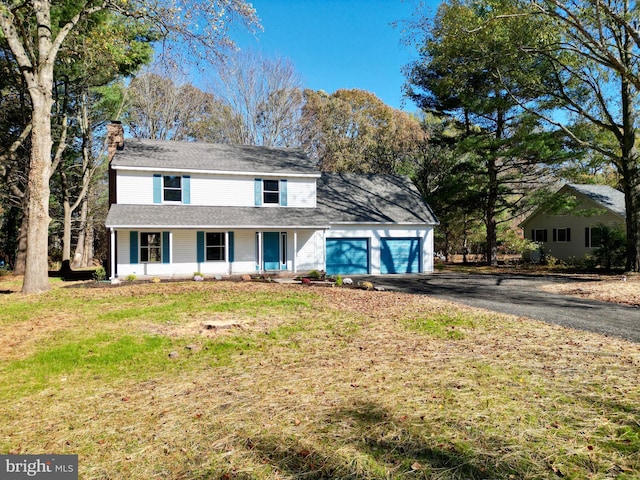 view of front property with a garage, covered porch, and a front lawn