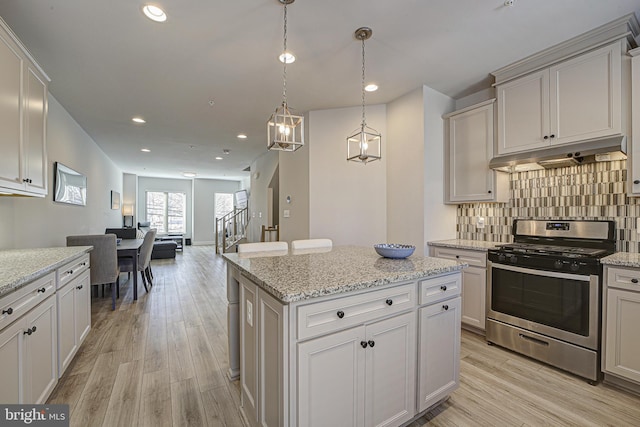 kitchen featuring light hardwood / wood-style floors, pendant lighting, stainless steel range with gas cooktop, and a kitchen island