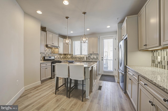 kitchen featuring light stone counters, stainless steel appliances, a breakfast bar, and a center island