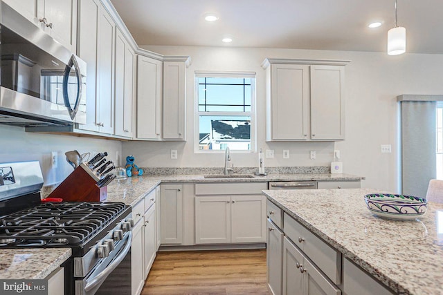 kitchen with light stone countertops, stainless steel appliances, white cabinetry, and sink