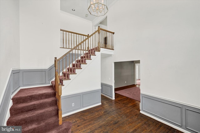 staircase with hardwood / wood-style flooring, crown molding, and an inviting chandelier